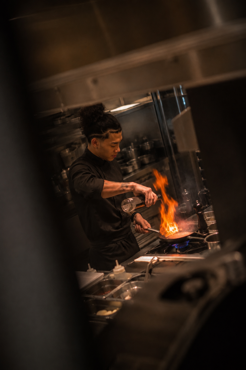Cuisinier en plein service, flambage à la poêle dans une cuisine professionnelle